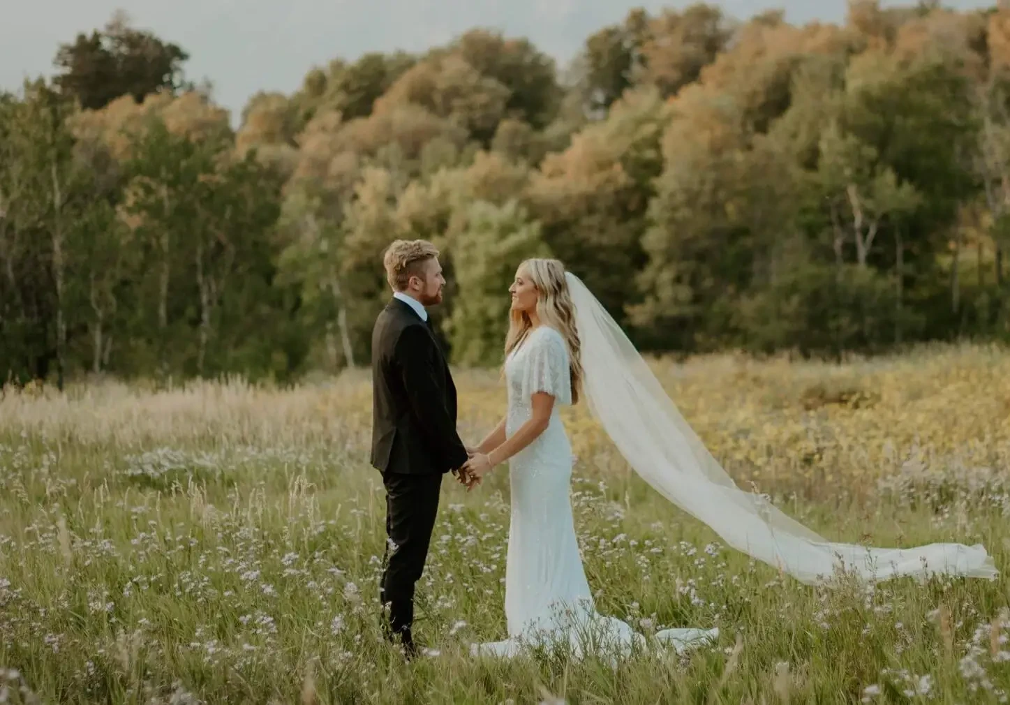 Image of a bride and groom posing hand to hand on a green scenery.