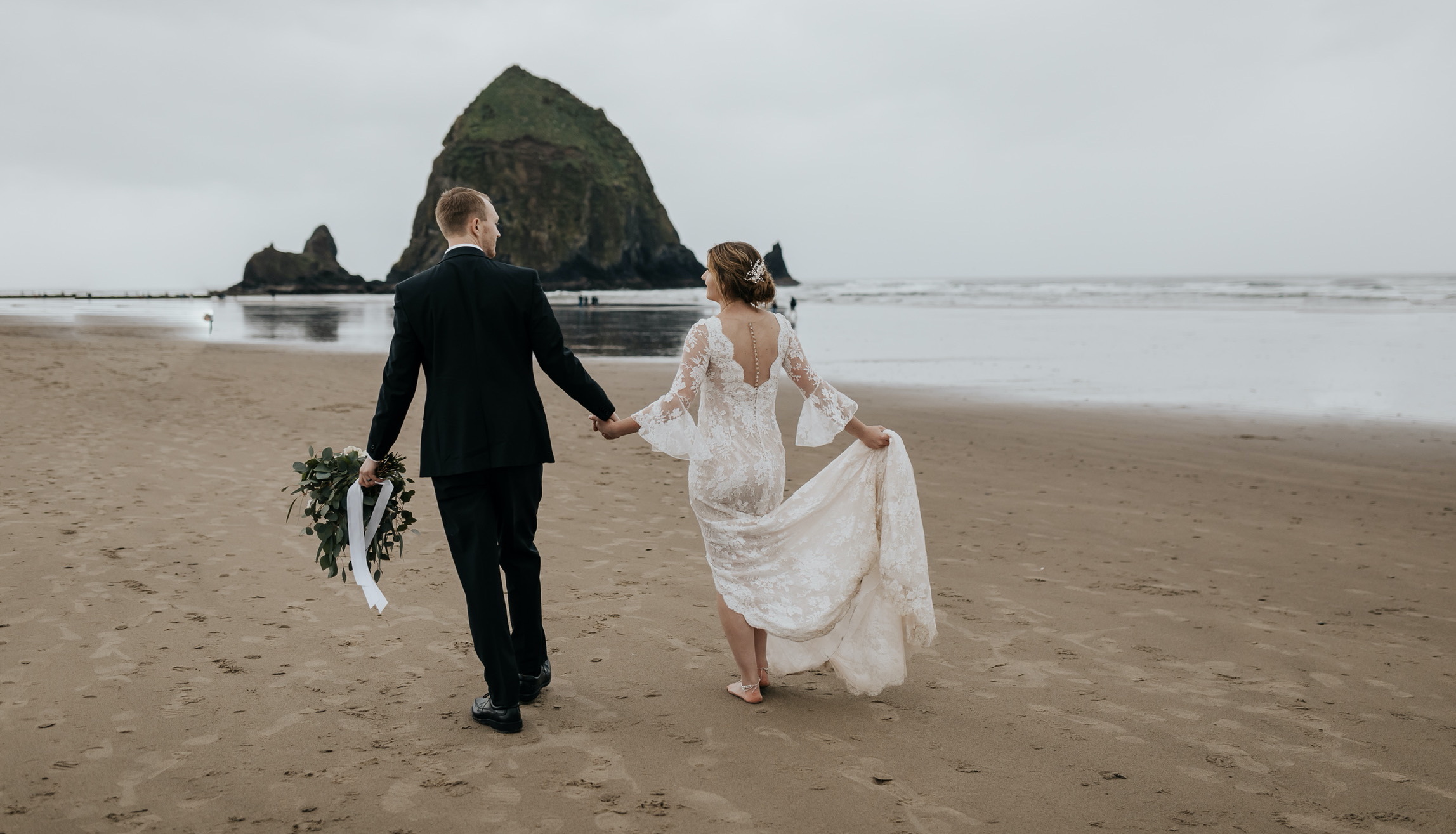 Сouple wearing a white gown and a black suit on the beach